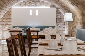 A restaurant with stone walls, wooden tables, and white table settings.