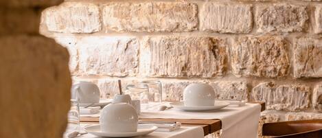 Interior de restaurante con paredes de piedra y mesas dispuestas para comer.