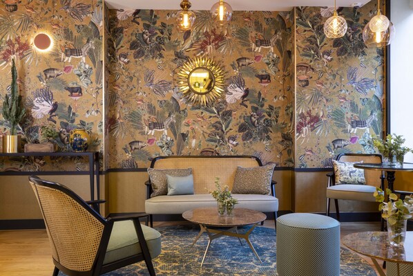 A room with a sofa, chairs, a round coffee table, and a patterned wall.