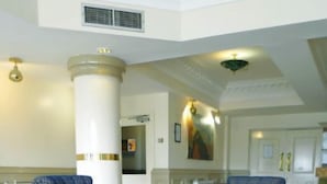 A spacious lobby with a large, ornate table and blue patterned chairs. - Roman Way Hotel A5 Cannock (Cannock)