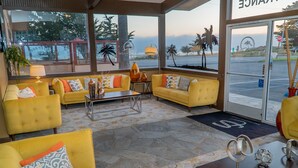 A hotel lobby with yellow sofas, a coffee table, and a view of the beach. - San Simeon Lodge (San Simeon)