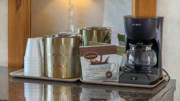A coffee machine, disposable cups, and a coffee pod on a tray.