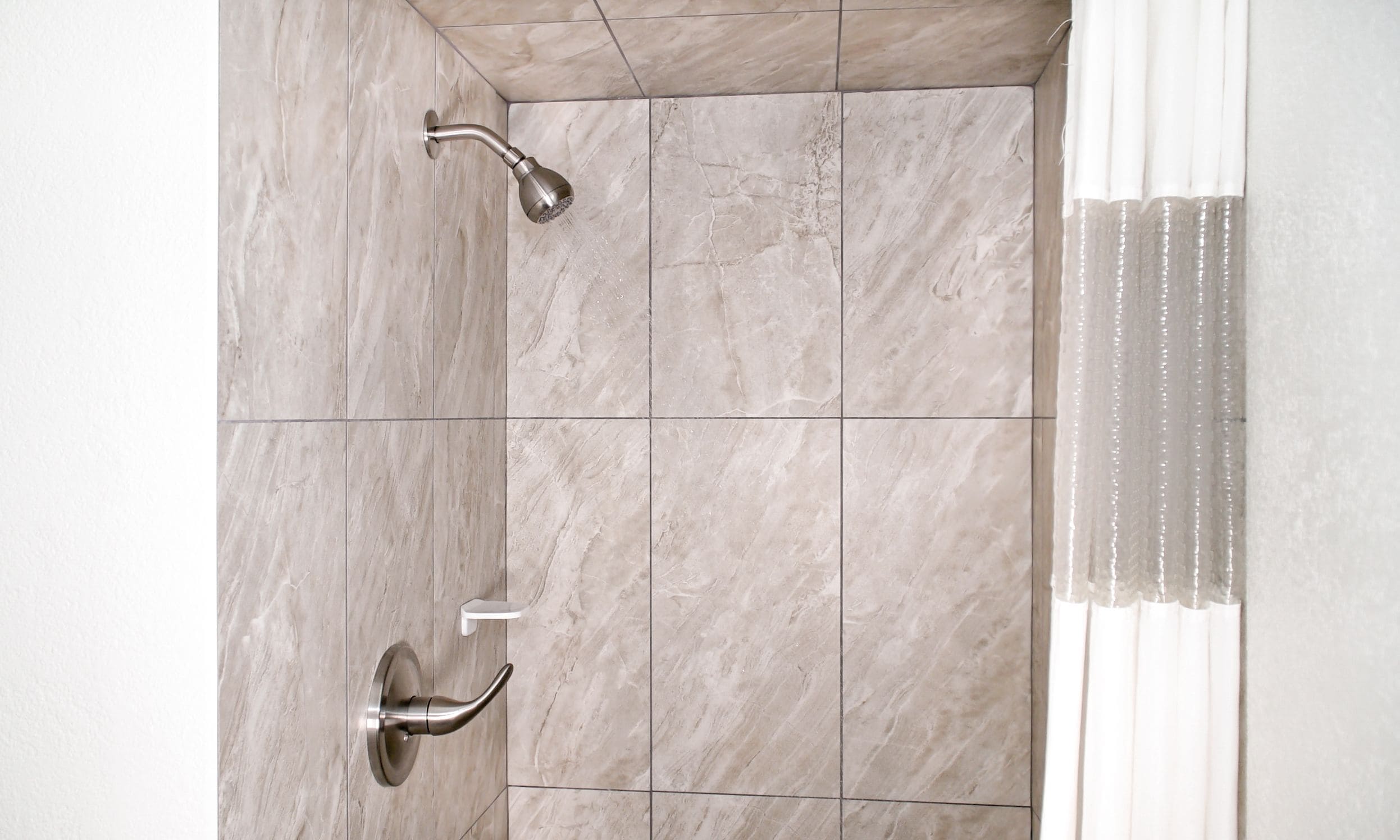 A bathroom with a shower, tiled walls, and a white sink.