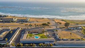 An aerial view of a coastal hotel with a swimming pool, parking area, and ocean views. - San Simeon Lodge (San Simeon)