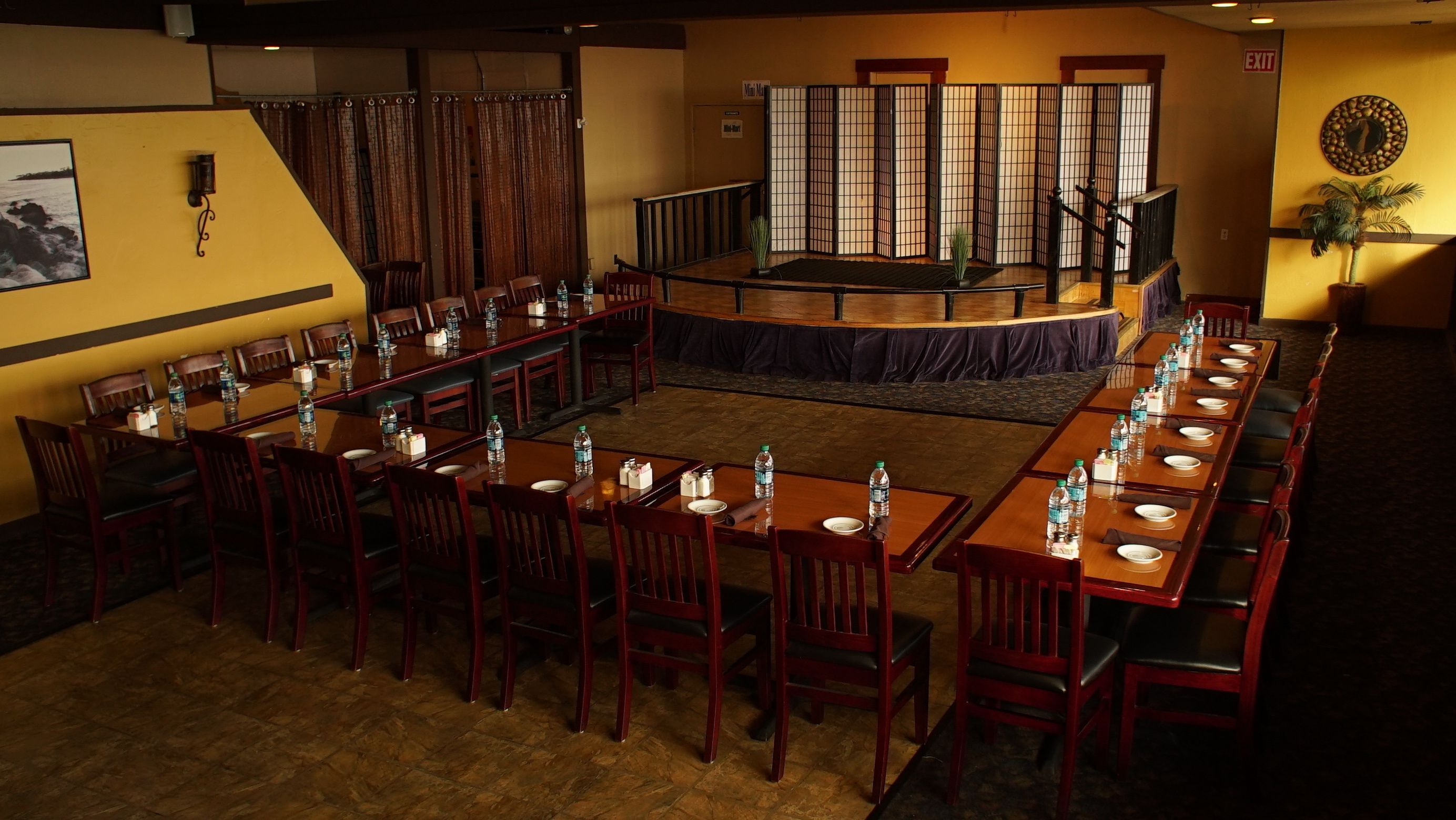 Een congrescentrum met lange tafels en stoelen, een podium en een traditionele Japanse kamerscherm.