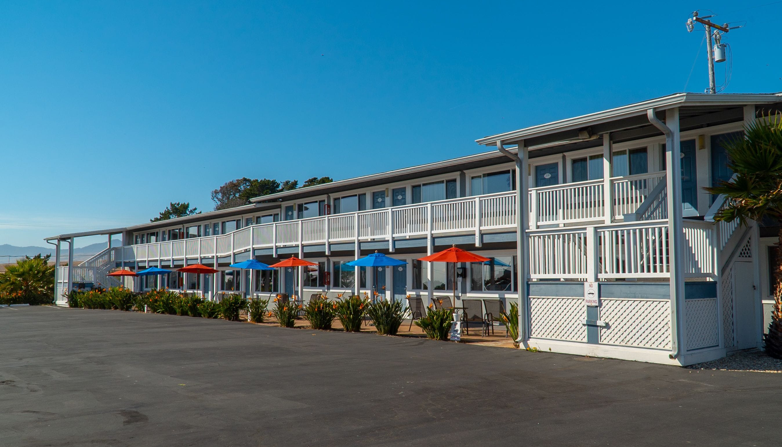 Un motel con varios balcones y zonas de estar al aire libre con sombrillas.