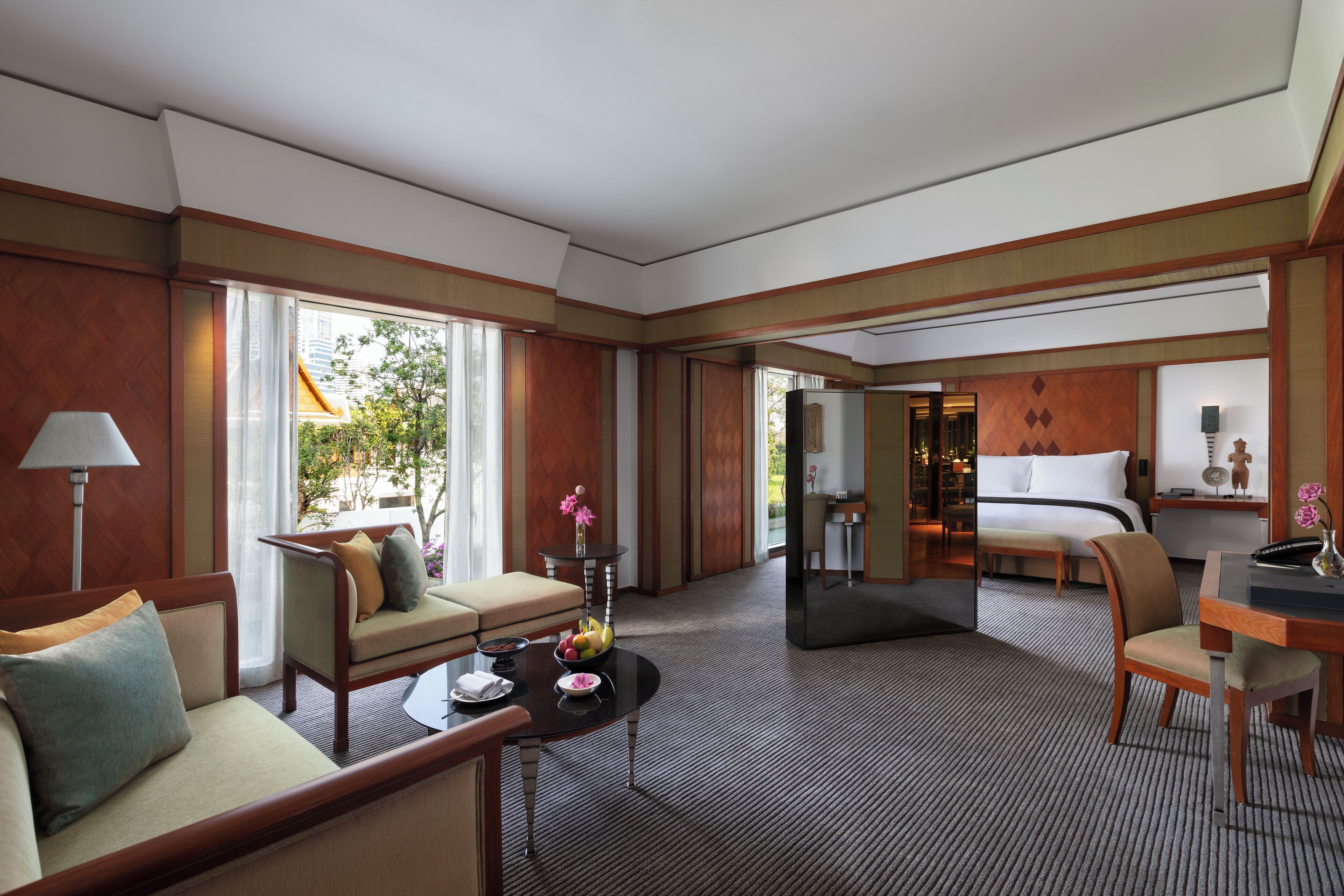 A hotel room with a sofa, a dining table, a bed, and a view of the outdoors.