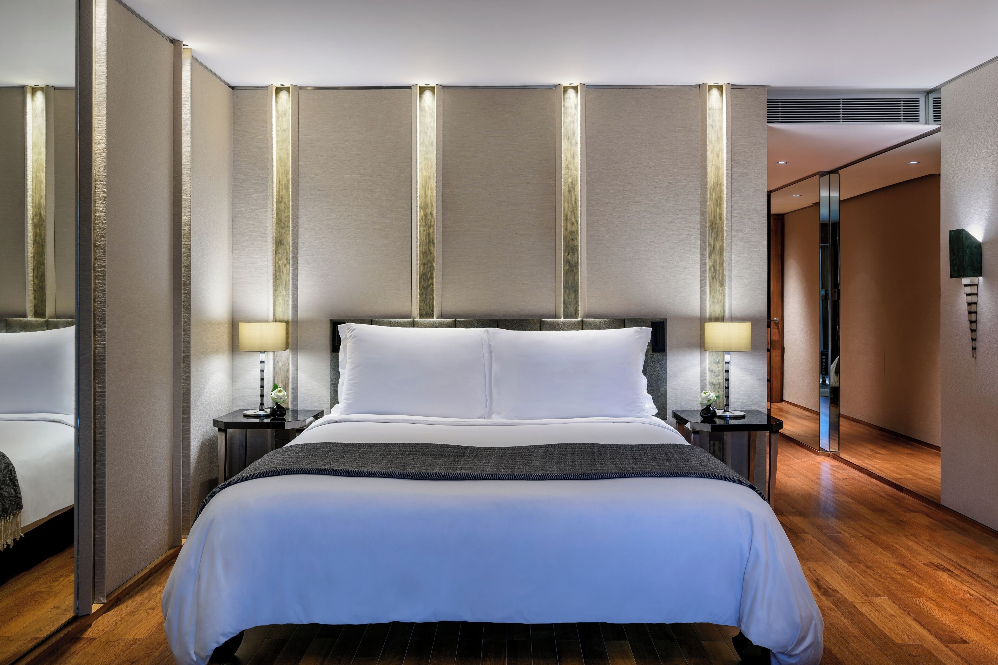 A hotel room with a large bed, bedside tables, and a mirror.