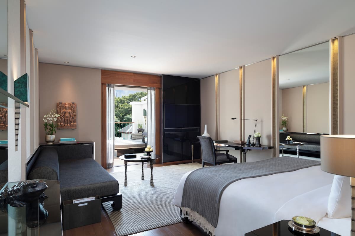 A modern hotel room with a large bed, a sofa, a desk, and a large mirror.