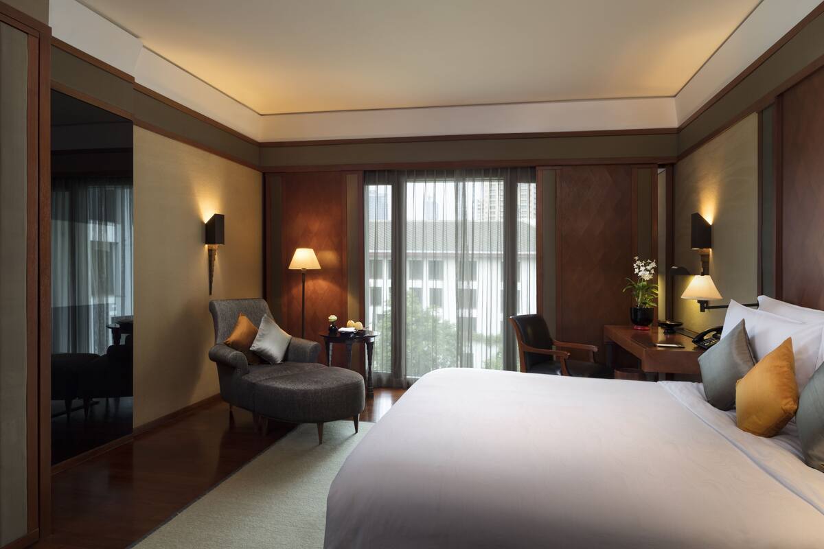 A hotel room with a large bed, a desk, a chair, and a sofa.
