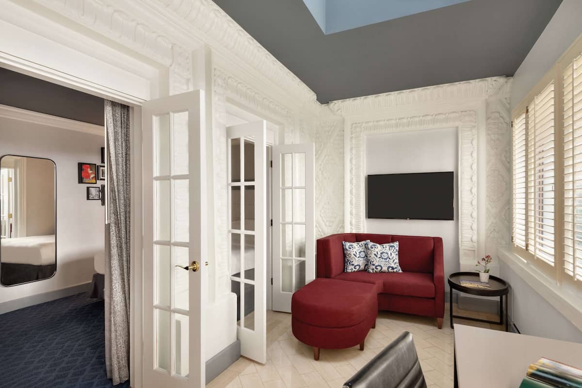 A spacious living room with a red sofa, a small round table, and a large mirror.