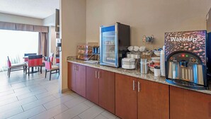 A hotel breakfast area with a coffee machine, a refrigerator, and a buffet counter. - Comfort Inn Elizabeth City near University (Elizabeth City)