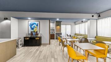A modern dining area with wooden flooring, yellow chairs, and a central counter with a coffee machine.