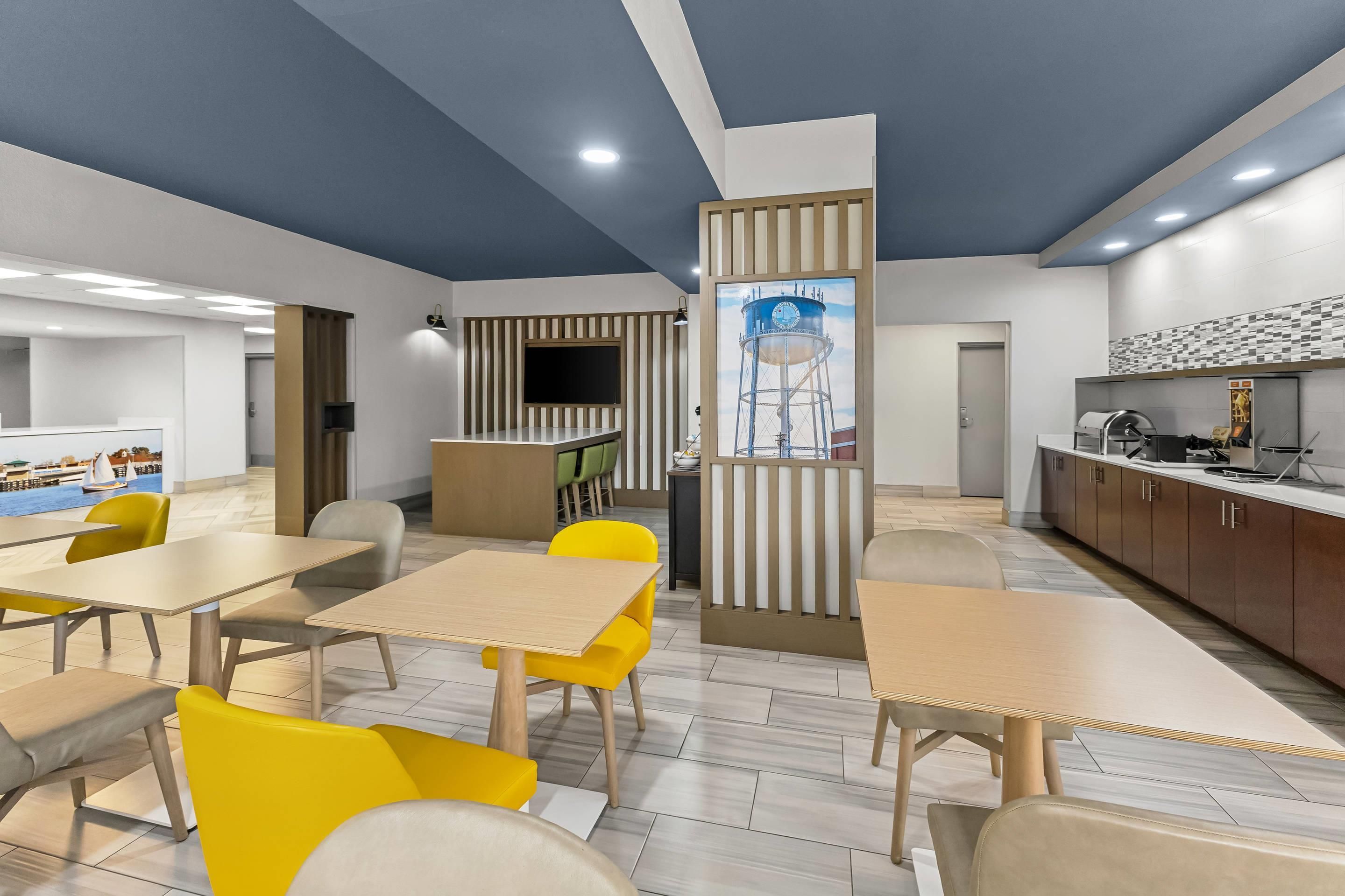 A modern interior with a dining area, kitchen, and a large window with a view.