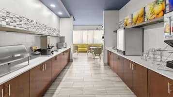 Una cocina moderna con una isla central, electrodomésticos integrados y una zona de comedor con sillas amarillas.