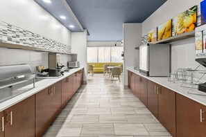 A modern kitchen with a central island, built-in appliances, and a dining area with yellow chairs. - Comfort Inn Elizabeth City near University (Elizabeth City)