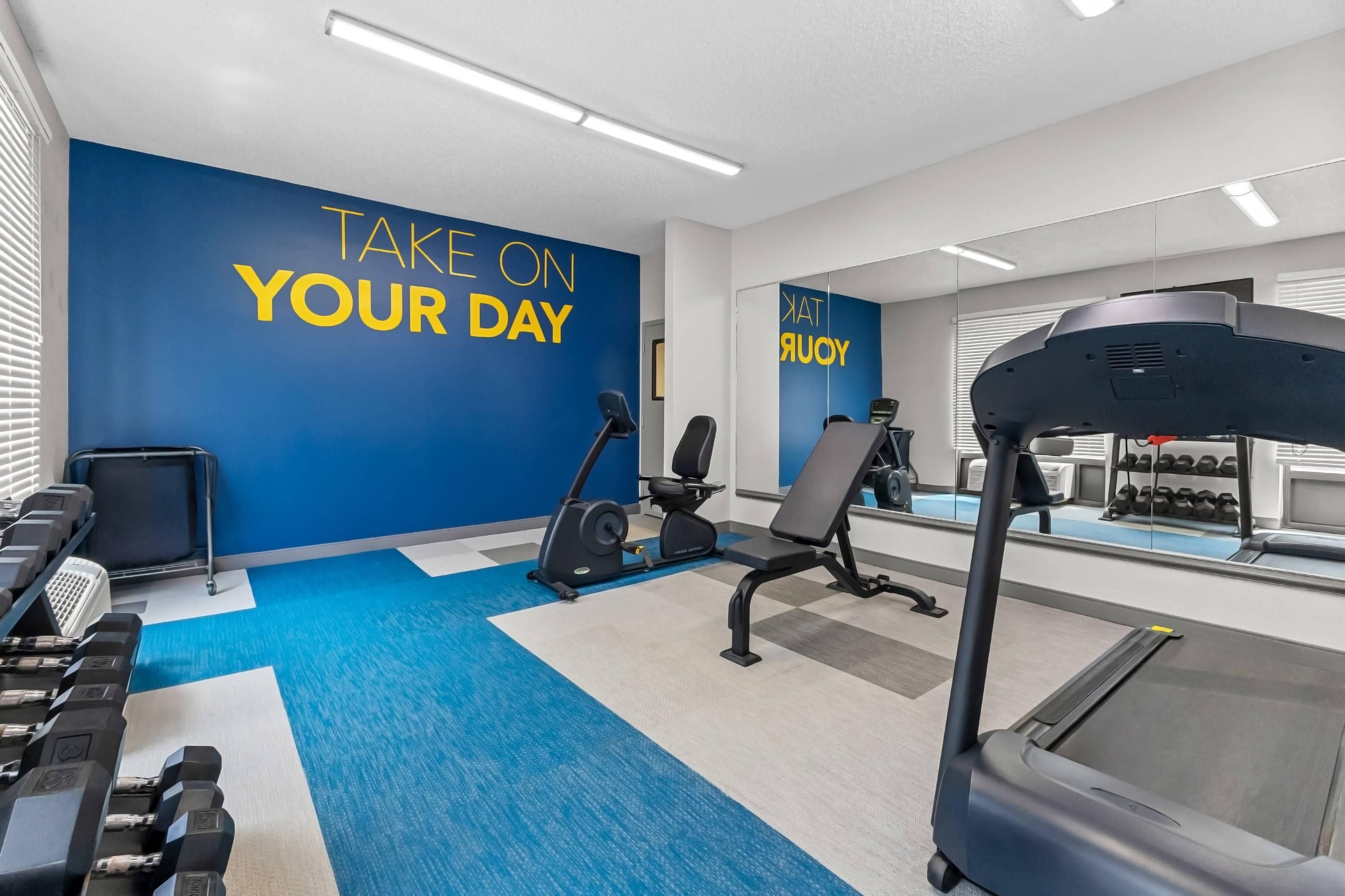 A gym with exercise equipment, a mirrored wall, and motivational text.