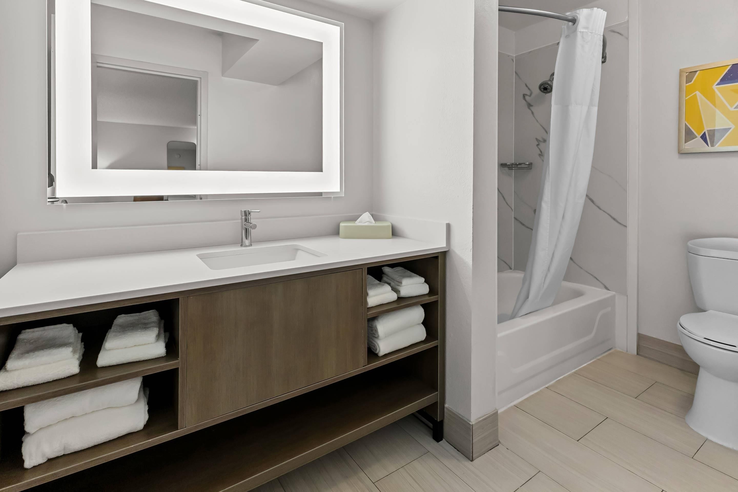 A modern bathroom with a white sink, mirror, and shower.