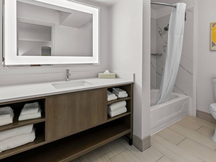 A modern bathroom with a white sink, mirror, and shower.