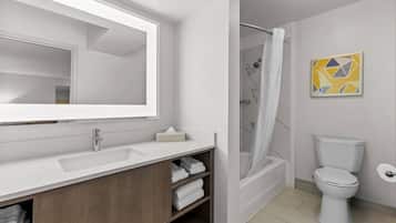 A modern bathroom with a large mirror, a shower, a toilet, and a towel rack.