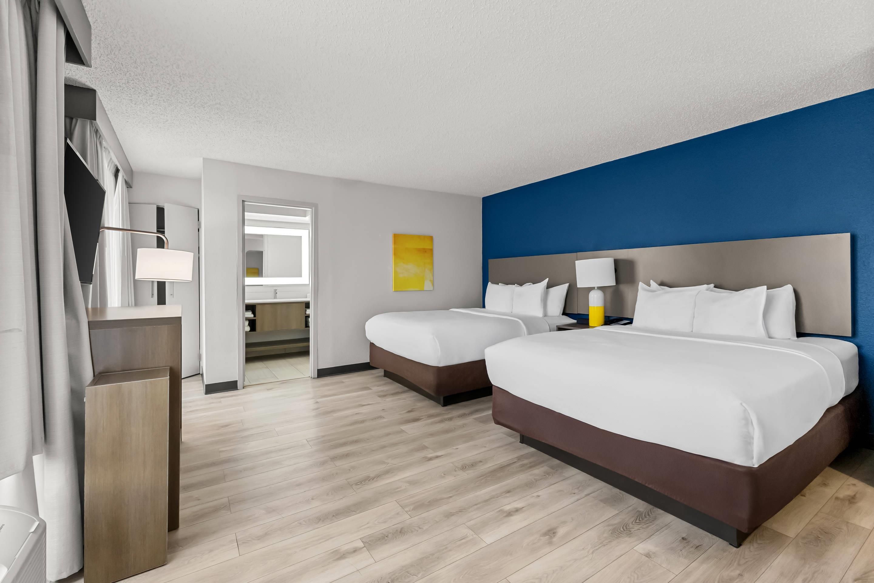 Une chambre d’hôtel avec deux lits, une salle de bain et vue sur le couloir.