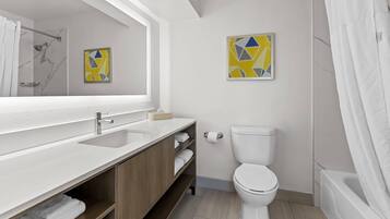 A modern bathroom with a large mirror, a sink, a toilet, and a shower.