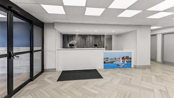 Zona de recepció de disseny modern, amb taulell d'informació, un ordinador penjat a la paret i un quadre d'una embarcació a vela.