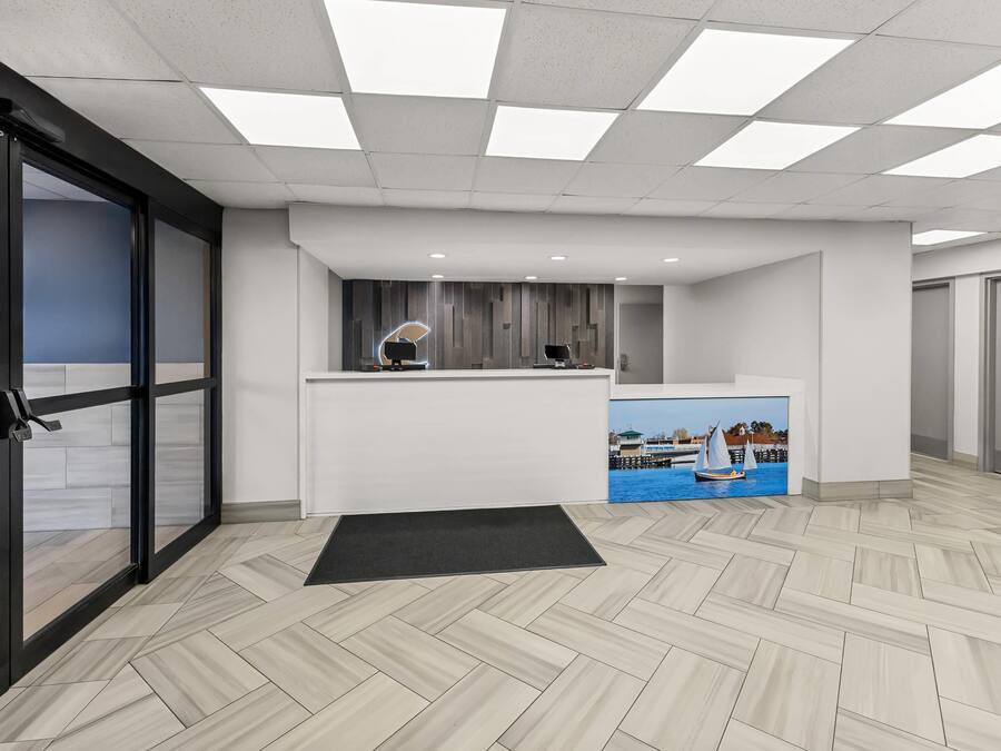 Zona de recepció de disseny modern, amb taulell d'informació, un ordinador penjat a la paret i un quadre d'una embarcació a vela.