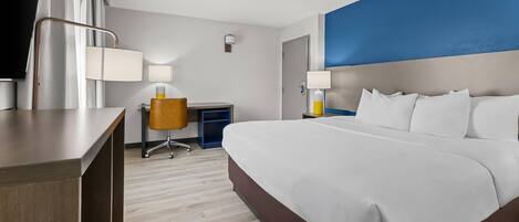 Una habitación de hotel con una cama grande, un escritorio, una silla y un televisor.