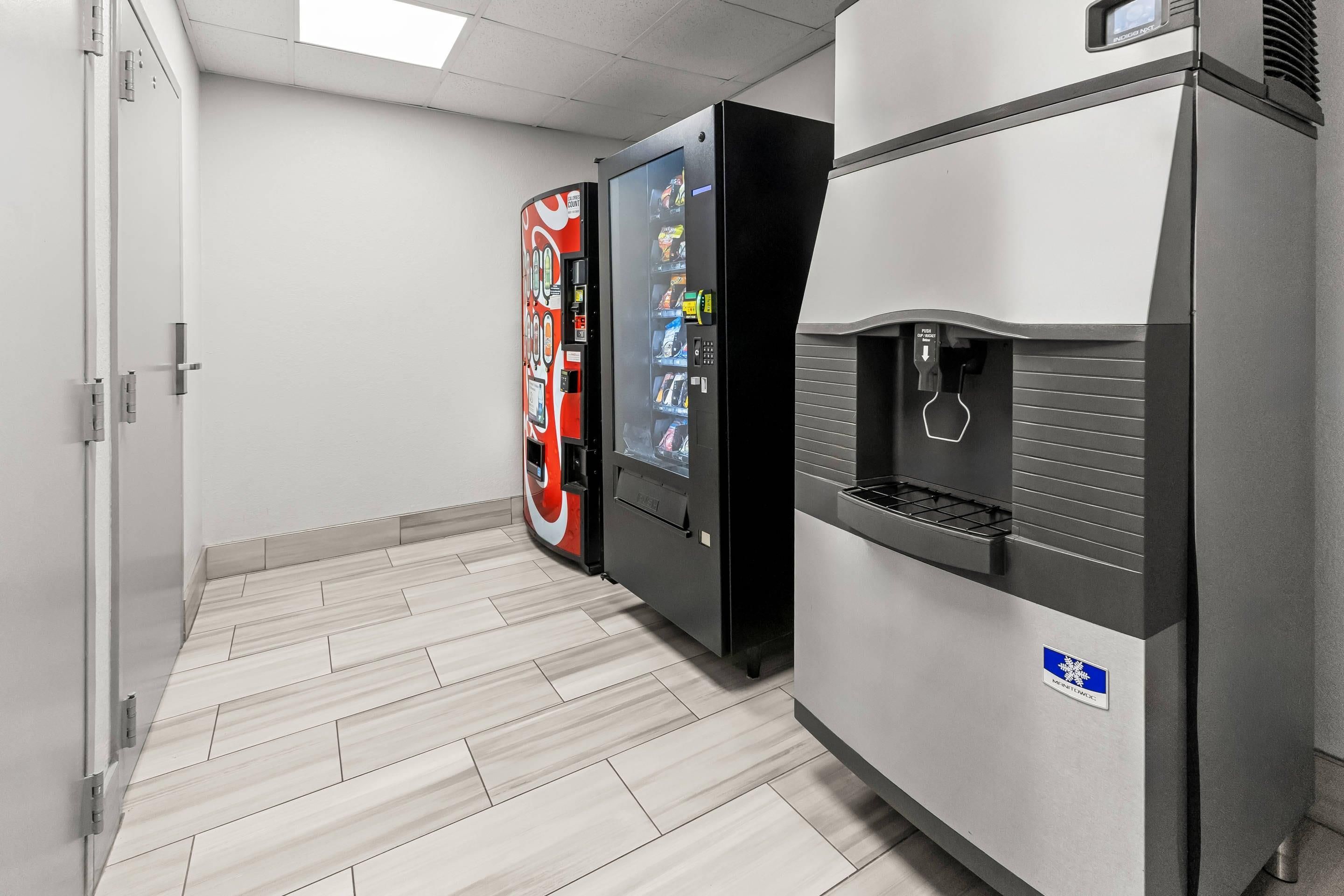 A vending machine and a water dispenser in a hallway with a tiled floor.