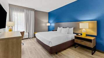 A hotel room with a bed, bedside tables, a desk, and a chair.