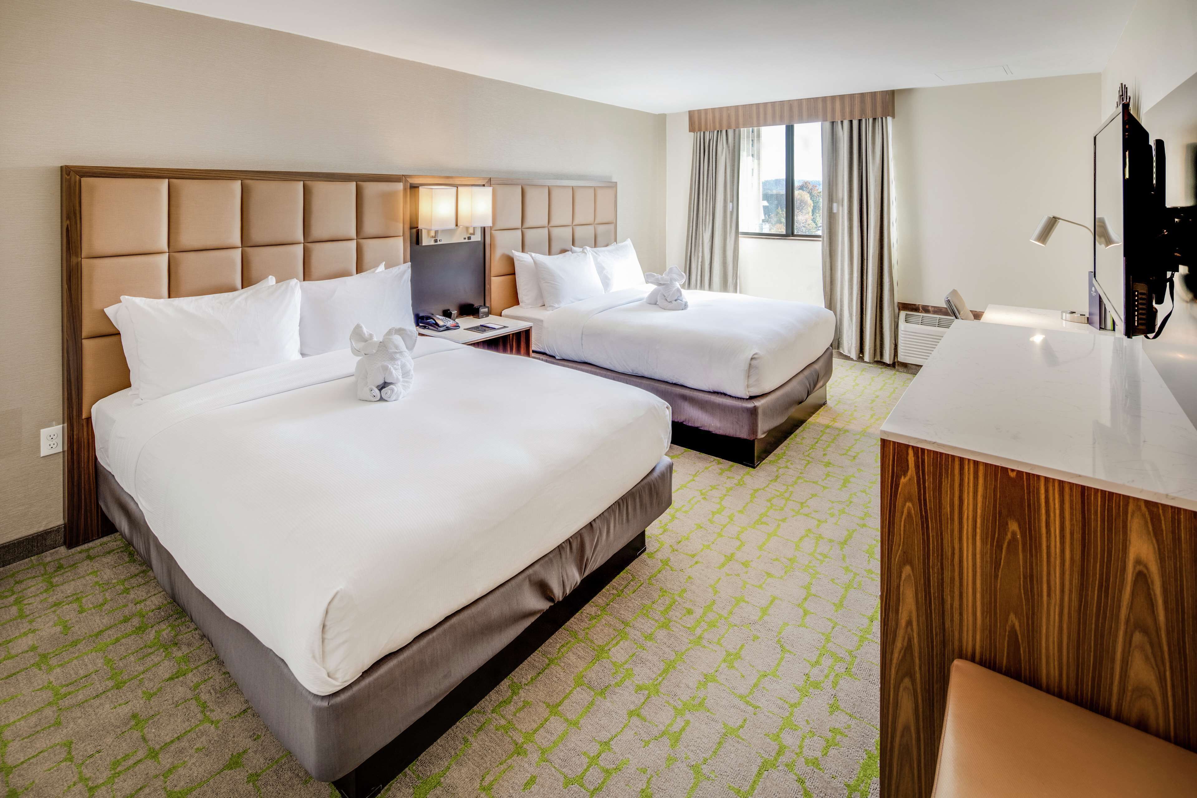 Een hotelkamer met twee bedden, een bureau en een badkamer.