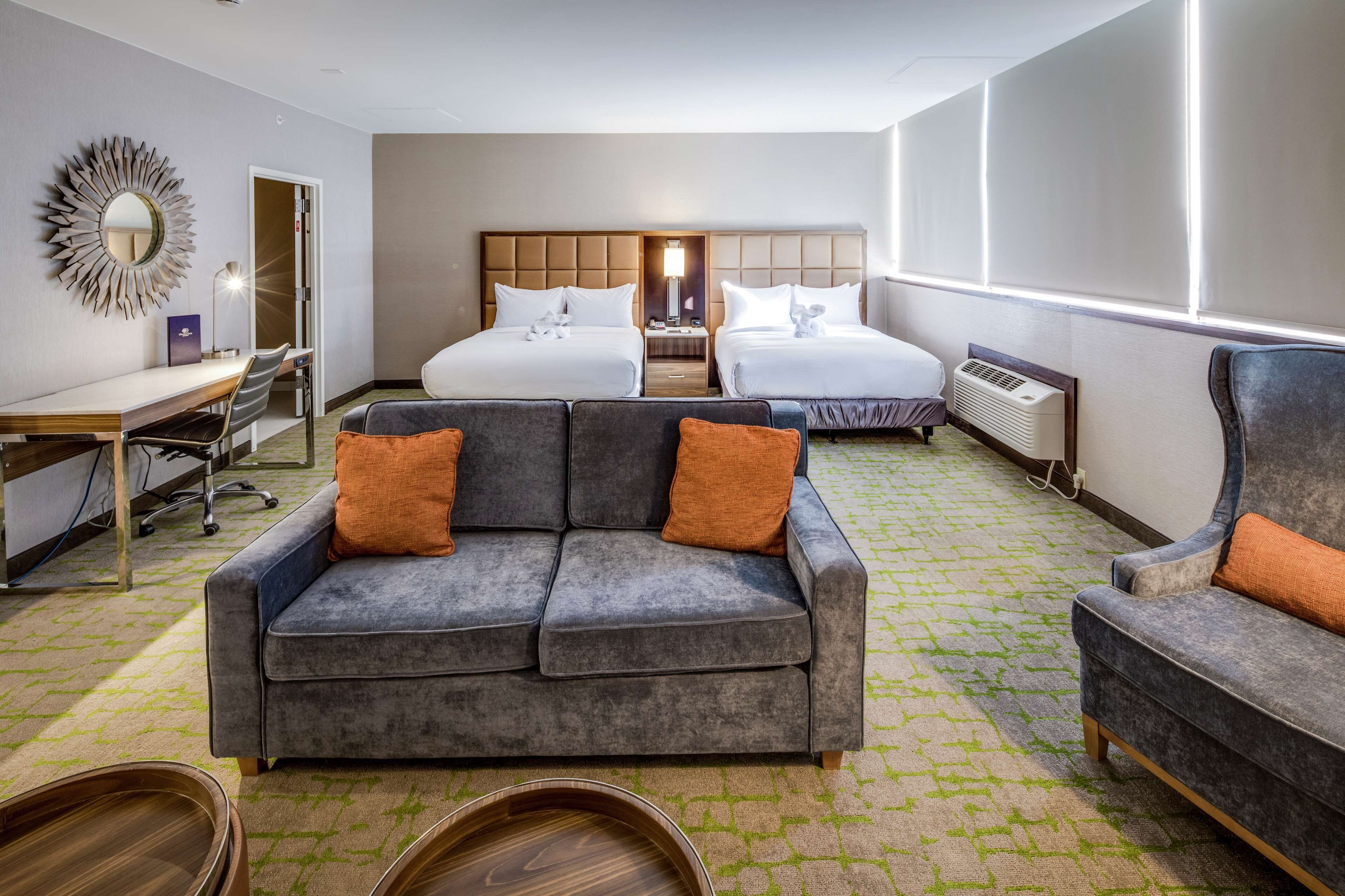 Een hotelkamer met twee bedden, een bank, een bureau en een stoel.