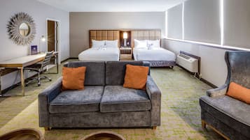 Een hotelkamer met twee bedden, een bank, een bureau en een stoel.