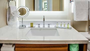 A bathroom with a white marble sink, a round mirror, and a towel rack.