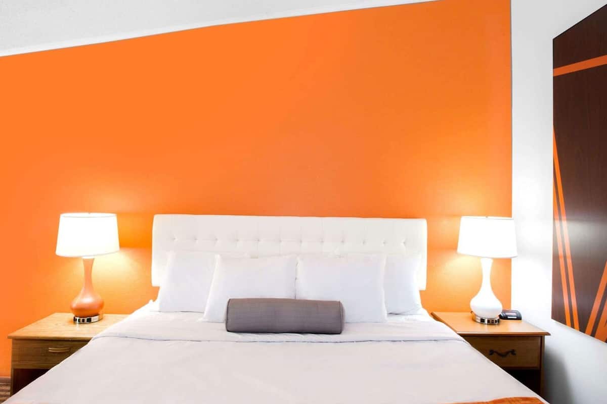 A bed with a white headboard, two bedside tables with lamps, and a single pillow.