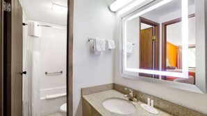 Un baño con lavamanos, espejo y ducha.