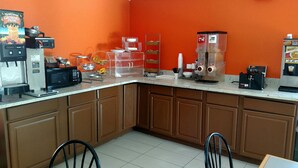 Una cocina con cafetera, licuadora y dispensador de vasos de fruta.