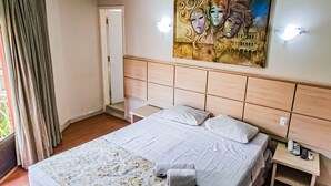 A hotel room with a bed, a nightstand, a painting, and a view of the outdoors. - Hotel Euro Suite São Paulo by Nacional Inn (São Paulo)