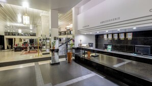 A modern hotel lobby with a reception desk, seating area, and a staircase leading to an upper level. - Hotel Euro Suite São Paulo by Nacional Inn (São Paulo)