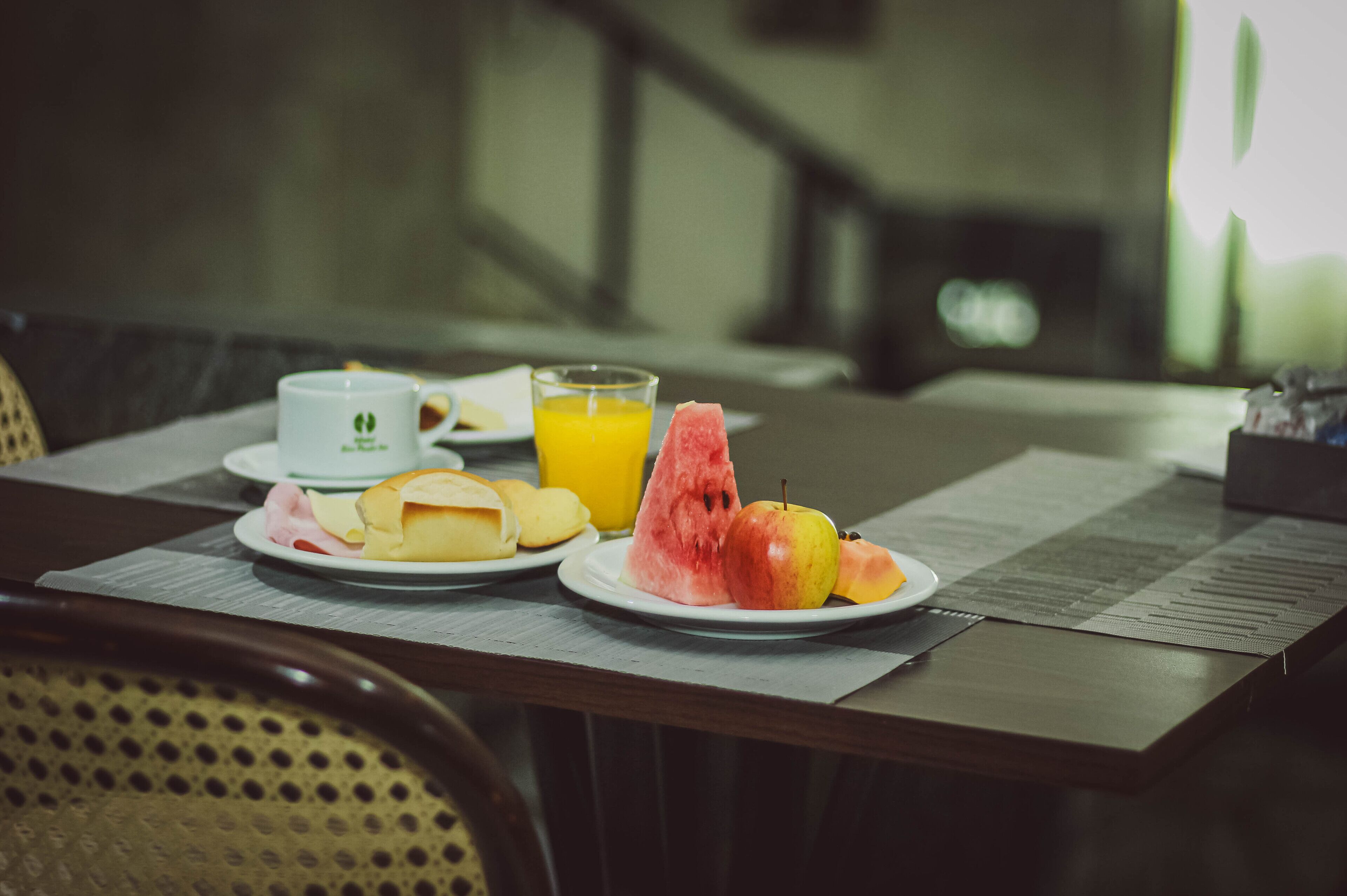 Una mesa de desayuno con platos de comida, un vaso de jugo de naranja y una taza.