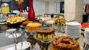 A buffet with various cakes and pastries, including a chocolate cake with a dripping effect, a bundt cake, and a bundt cake with a ring on top. - Hotel Euro Suite São Paulo by Nacional Inn (São Paulo)