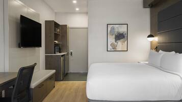 Ein modernes Hotelzimmer mit Bett, Schreibtisch, Fernseher und einem Bild an der Wand.