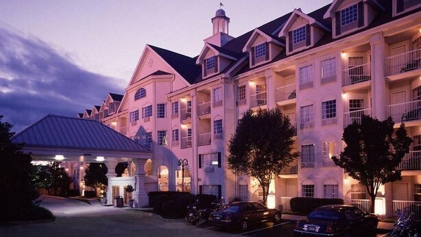 A multi-story hotel with a symmetrical facade, large windows, and a central entrance with a covered area. - Hotel Grand Victorian (Branson)