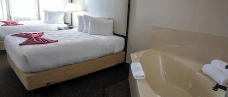 A hotel room with two beds, a large bathtub, and a nightstand with a lamp.
