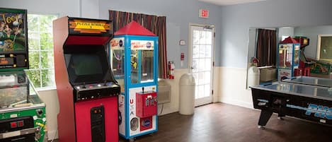Una habitación con juegos de arcade, una mesa de billar y una puerta con el letrero "EXIT".
