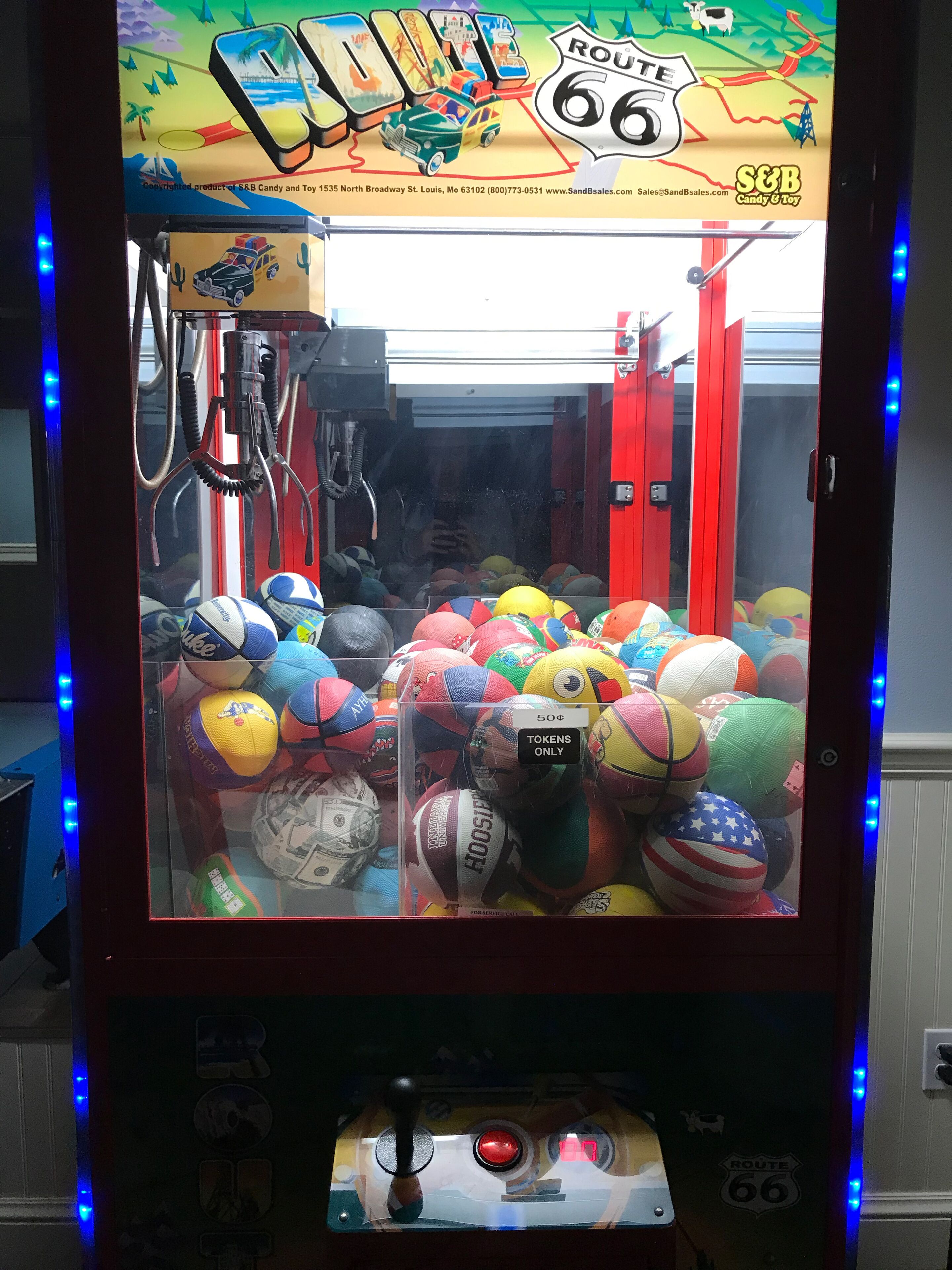 A claw machine filled with various sports balls.