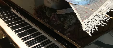 A grand piano with a floral arrangement and a decorative box on its stand.
