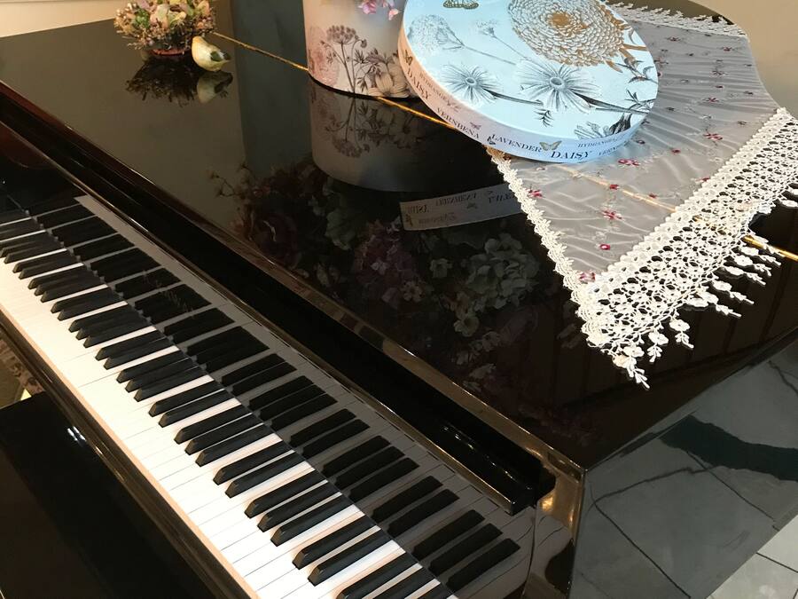 A grand piano with a floral arrangement and a decorative box on its stand.