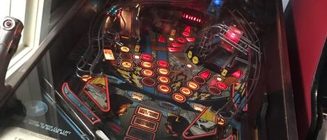 Una máquina de pinball con un letrero de neón que dice "CRÉDITOS O. INSERTAR MONEDA" y una etiqueta que indica "2 FICHAS".